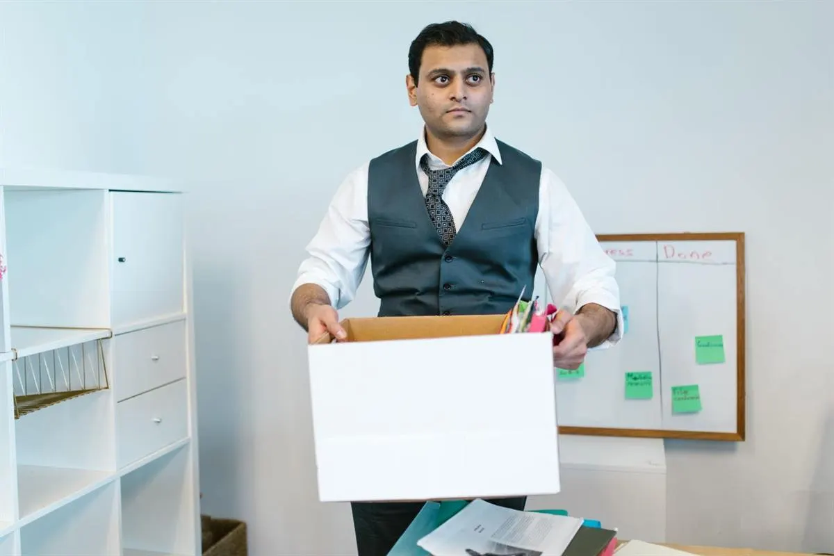 Office staff packing desk belongings into a carton before office shifting